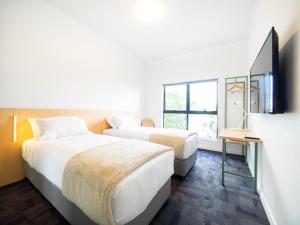布里斯班YHA Brisbane City的一间酒店客房,设有两张床和电视