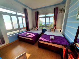 惹岛Thanh Tran Guesthouse Lý Sơn的一间卧室设有两张带紫色床单和窗户的床。