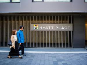 京都Hyatt Place Kyoto的男人和女人在一处栖息地前走