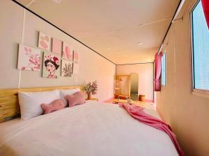 潘切Suly's Village Phan Thiết的卧室配有带粉红色枕头的大型白色床