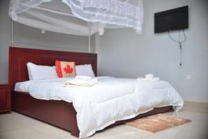 MbaleElgon Palace Hotel - Mbale的一间卧室配有一张带白色床单的床和电视。