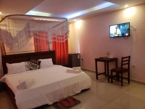 MbaleElgon Palace Hotel - Mbale的卧室配有一张床,墙上配有电视。