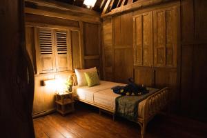乌布Green Bird Villa - CHSE Certified的木制客房内的一间卧室,配有一张床