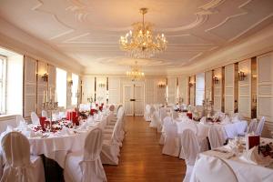 讷凡姆伊恩涅德巴Schlosshotel Neufahrn的宴会厅配有白色的桌椅和吊灯