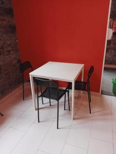 卢阿尔卡Albergue de Peregrinos Villa de Luarca的一张带两把椅子的白色桌子和红色的墙壁