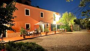 LarcianoAgriturismo Podere Marchiano的一座橙色的建筑,配有桌椅和遮阳伞