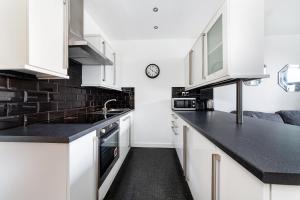 锡豪西斯McLaren House Seahouses的厨房配有白色橱柜和黑色台面