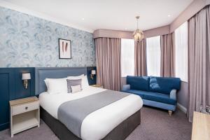 布罗姆利伦敦布罗姆利法院酒店的酒店客房,配有一张床和一张蓝色椅子