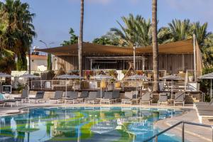 帕福斯King Jason Paphos - Designed for Adults by Louis Hotels的一个带桌椅的游泳池和一间酒吧