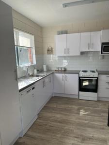 杰拉尔顿Harbour View 49 Urch Street Unit 4的厨房配有白色橱柜、水槽和炉灶。