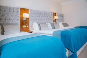 韦斯特波特怀亚特酒店的两张位于酒店客房的床,配有蓝色床单
