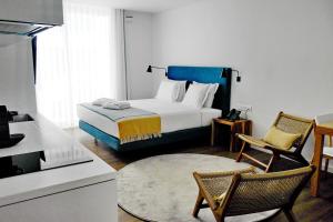 蓬塔德尔加达Pêro Teive Bay Apartments Hotel的一间卧室配有一张床和两把椅子,还设有一间厨房