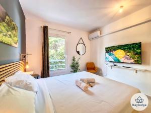 圣皮埃尔T3 - Tropical Lodge - 3 étoiles - 65m2 - Saint-Pierre的卧室配有白色的床和墙上的电视。