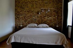 EckelradeDe Moolt Vakantiewoningen的一间卧室设有砖墙和一张带两个枕头的床