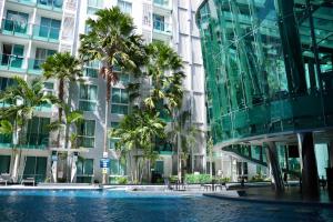 芭堤雅市中心City Center Residence & Yahaha的棕榈树建筑前的游泳池