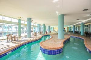 默特尔比奇1 Bedroom Suite with City and Partial Ocean Views- Bay View Resort 702的大楼内带桌椅的游泳池
