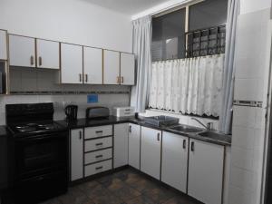 马盖特Marlicht Vacation Resort的一间小厨房,配有白色橱柜和黑色家电