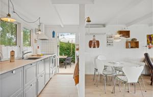 森讷比Stunning Home In Juelsminde With Wifi的厨房配有白色橱柜和桌椅