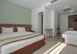 马瑙斯维尔弗斯机场快线酒店的一间卧室配有一张大床和一张书桌