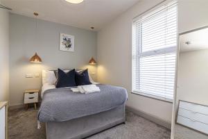 德比Stay @ Baker Street Derby的一间卧室配有一张带蓝色枕头的床和一扇窗户。