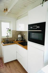 诺德韦克Tiny House Noordwijk aan Zee的厨房配有白色橱柜和黑炉灶烤箱。