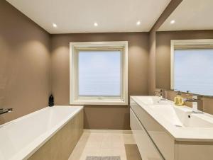 奥斯陆Cozy House的一间带两个盥洗盆和浴缸的浴室以及两个窗户。