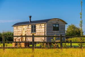 伍斯特Monkwood Shepherds Hut - Ockeridge Rural Retreats的铁栅后面的黑色屋顶木房子