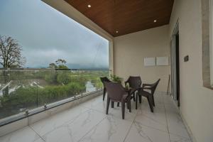罗纳瓦拉Mountain Majesty Villa by Tropicana Stays的阳台配有桌椅和大窗户。