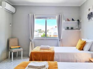 卡武埃鲁CASA TÔMBUA - Pool - Beach & Center 300m - AC - WiFi的一间卧室设有两张床和窗户。