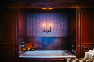 因弗雷里The George Hotel的浴室设有浴缸,墙上挂有两根蜡烛