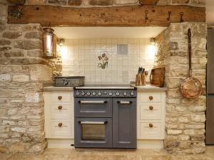 切尔滕纳姆Manor Farm的厨房配有炉灶和石墙