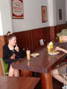 不拉士打宜Hotel Mexico Berastagi的坐在餐桌上吃食物的女人
