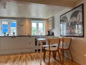 瑟沃格Cory & Torfinn House的厨房配有白色橱柜和桌椅