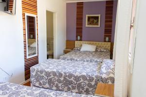 波苏斯-迪卡尔达斯Hotel Fazenda Poços de Caldas的紫色墙壁客房的两张床