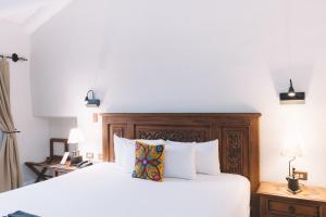 库斯科安提瓜卡索纳圣布拉斯酒店的卧室配有白色的床和木制床头板