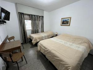 Rosario罗萨里奥酒店的一间卧室配有两张床、一张桌子和一张书桌