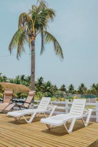 EscuintlaLos Olivos La Playa Hotel y Restaurante的四把躺椅和木甲板上的棕榈树