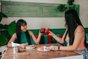 麦德林Cordova Hostel Medellin的两个坐在桌子边喝着饮料的女人