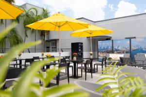 迈阿密海滩Fashion Boutique Hotel的庭院配有桌椅和黄色遮阳伞