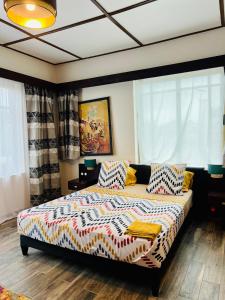 科托努La Villa Saint Jean的一间卧室配有一张带色彩缤纷的床单和枕头的床。