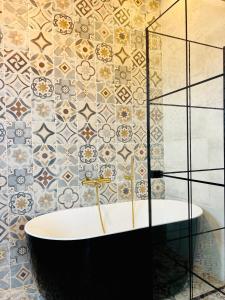 科托努La Villa Saint Jean的带浴缸和瓷砖墙的浴室