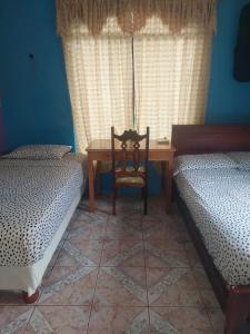 巴克里索莫雷诺港C.C. Habitaciones的一间卧室配有两张床、一张桌子和一把椅子