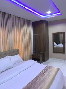 阿布贾Executive Royal Suite Kado的卧室配有白色床和紫色天花板
