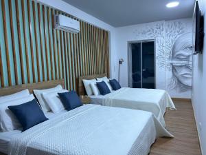 RoldanilloHotel Cocli的酒店客房设有两张床,墙上挂有绘画作品