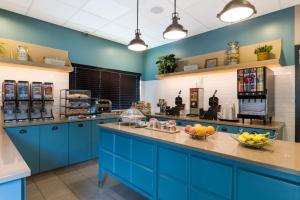威奇托Country Inn & Suites by Radisson, Wichita East, KS的一间大厨房,厨房内有蓝色的橱柜和水果台