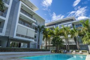 蓬塔卡纳Lumina at Palms Punta Cana Village的公寓大楼设有游泳池和棕榈树