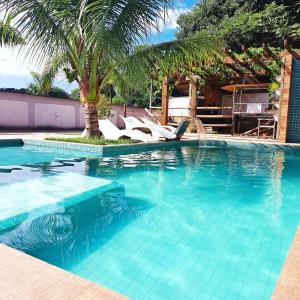 里约热内卢Casa com piscina e muita tranquilidade的一个带椅子的游泳池,并种植了棕榈树