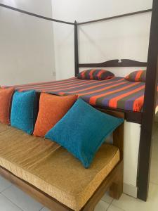 MalwanaSavenndra Resorts的两张床铺,配有多彩的枕头,位于长凳上