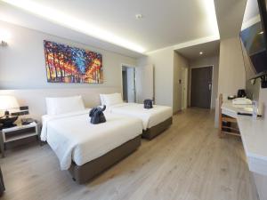 清迈乐纳优@普拉欣酒店的酒店客房设有两张床,墙上挂有绘画作品