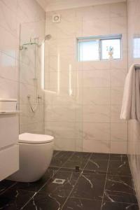 悉尼Churchill’s Rest的一间带卫生间和玻璃淋浴间的浴室